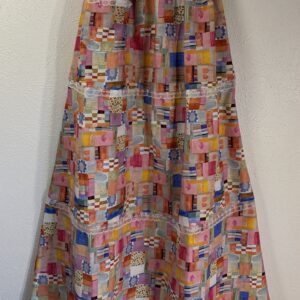 patchwork print skirt, front view, various patchwork prints, pink + orange color palette, 3 tiers ending with lace, one front pocket